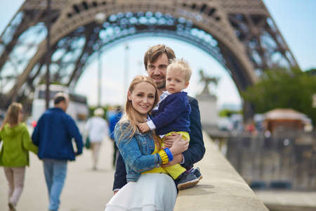 Happy family of three having fun together in Paris near the Eiffel towerの写真素材