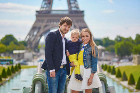 Happy family of three having fun together in Paris near the Eiffel towerの写真素材