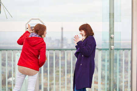 Two beautiful young girls in Paris looking at the Eiffel tower from the Montparnasse towerの写真素材
