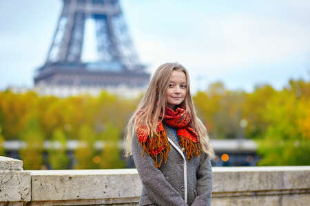 Beautiful young woman in Paris walking near the Eiffel tower on a beautiful colorful autumn dayの写真素材