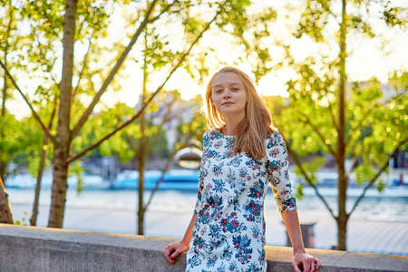 Young beautiful and elegant Parisian woman in blue dress near the Seine in Parisの写真素材