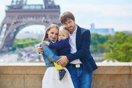 Happy family of three having fun together in Paris near the Eiffel towerの写真素材
