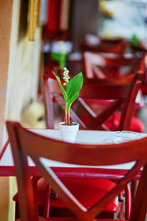 Table of Parisian outdoor restaurant decorated with lilies of the valley flowersの写真素材
