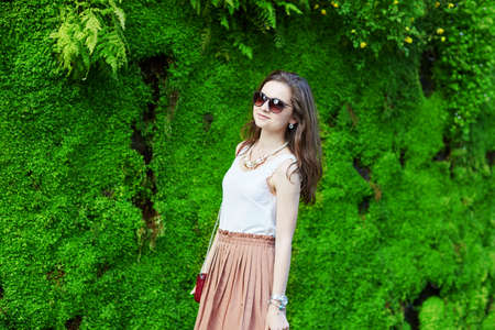 Beautiful young Parisian woman near the wall covered with green plantesの写真素材