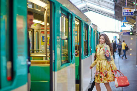 Beautiful young woman running to catch a train on the platform of Parisian subwayの写真素材