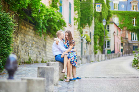 Romantic couple having a date early morning on Montmartre, Paris, sitting in the street and kissingの写真素材