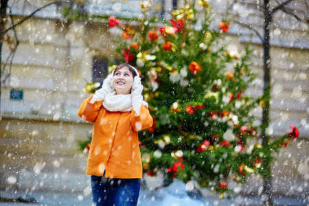 Girl with a brightly decorated Christmas tree in Paris during snowfall