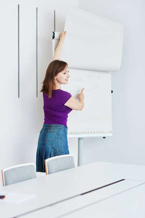 Pretty young student or business woman writing on a paper board during a class or business meeting