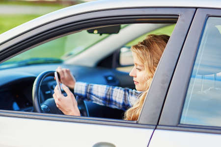 Young woman using her smartphone while driving a car