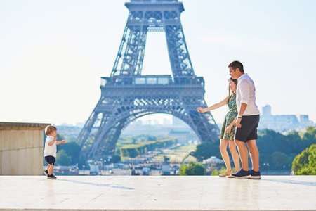 Adorable little boy making his first steps in Paris near the Eiffel towe and running to his parentsの写真素材