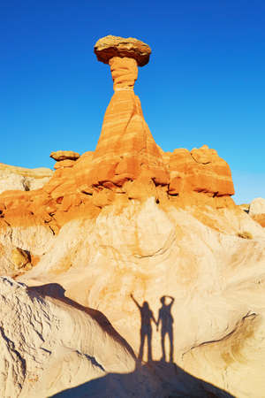 Traveling couple making funny picture of their shadow under the giant hoodoo rock formation in Arizona, USAの写真素材