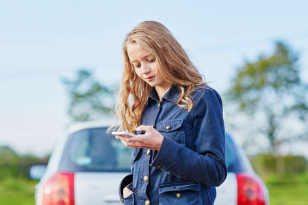 Young woman on the road near a broken car calling for help