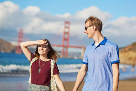 Romantic loving couple having a date on Baker beach in San Francisco, California, USA. Golden gate bridge in the backgroundの写真素材