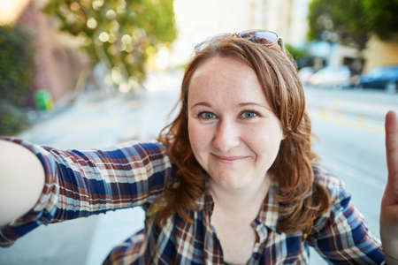 Cheerful girl taking selfie on a street of San Francisco, California, USA