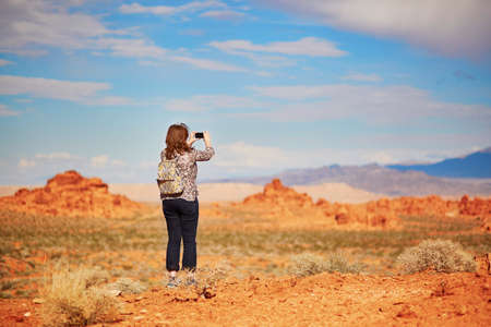 Tourist taking photo with her mobile phone in Valley of the Fire national park, Nevada, USA