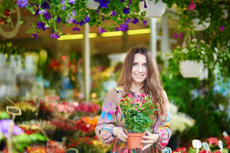 Beautiful young customer selecting fresh flowers in Parisian flower shop or on marketの写真素材