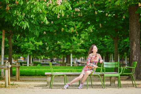 Beautiful young woman in the Tuileries garden, walking under chestnut trees in full bloomの写真素材