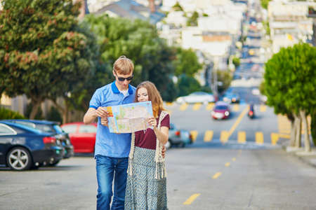 Romantic couple of tourists using map and planning their itinerary in San Francisco, California, USA
