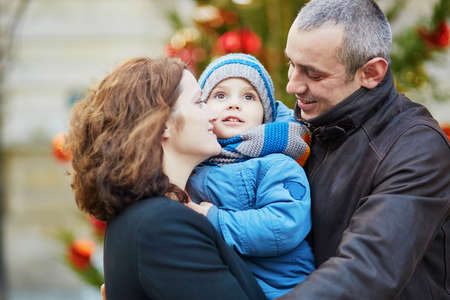 Happy family of three walking together on a street of Parisの写真素材