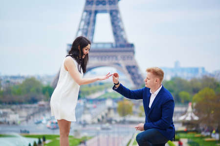 Romantic engagement in Paris, man proposing to his beautiful girlfriend near the Eiffel tower.の写真素材