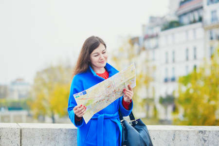 Beautiful young tourist in Paris, using map near Notre-Dame cathedral