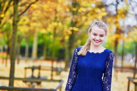 Beautiful young woman in blue dress in the Luxembourg garden of Paris on a fall day