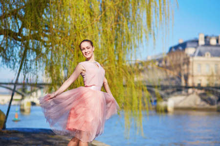 Beautiful young woman in pink dress dancing in Paris near the river Seineの写真素材