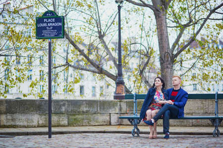 Young romantic couple sitting together on a bench on a Parisian streetの写真素材