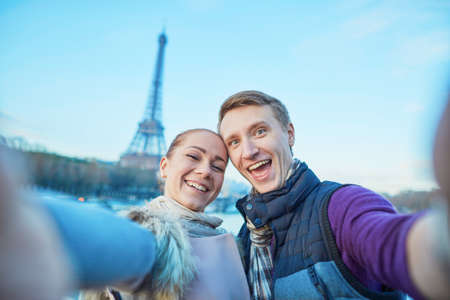 Happy couple of tourists having fun and taking selfie near the Eiffel tower in Parisの写真素材