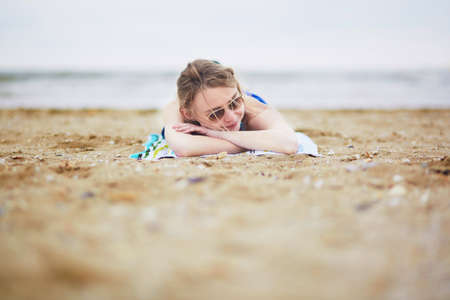 Beautiful young woman relaxing and sunbathing on sand beachの写真素材