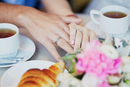Just married couple holding hands in Parisian cafe on their wedding dayの写真素材