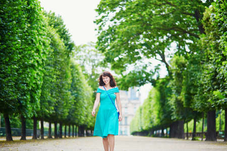 Beautiful young woman walking in Parisian Tuileries park on a summer dayの写真素材