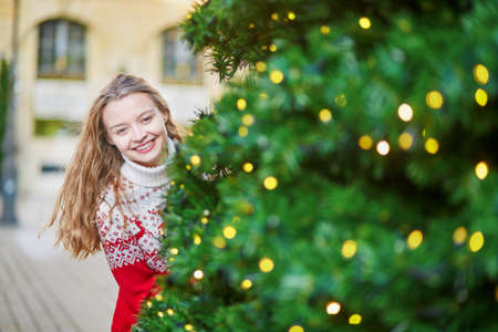 Cheerful young woman on a street of Paris decorated for Christmasの写真素材
