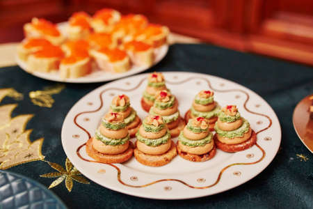 Table set for Christmas dinner with delicious appetizers - fois gras sandwiches in form of little Christmas treesの写真素材