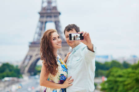 Romantic loving couple having a date near the Eiffel tower and making selfie with their mobile phone.の写真素材
