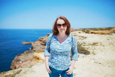 Beautiful young woman at rocky coastline in Algarve region of Portugalの写真素材