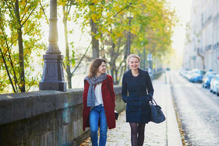 Two young girls walking together in Paris on a sunny fall day. Tourism or friendship conceptの写真素材