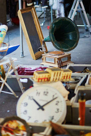 Old clock and gramophone on flea market in Paris, France. Focus on gramophone