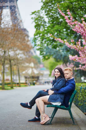 Happy couple near the Eiffel tower. Tourists enjoying their vacation in France. Romantic date or traveling couple conceptの写真素材