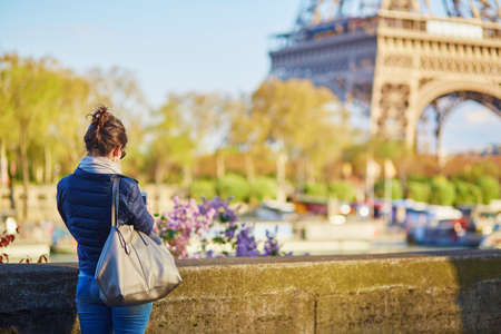 Tourist on the Seine embankment taking photo of the Eiffel tower in Paris, Franceの写真素材