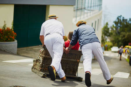 Famous toboggan riders moving traditional cane sledge downhill on the streets of Funchal, Madeira island, Portugalの写真素材