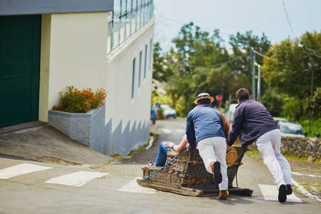 Famous toboggan riders moving traditional cane sledge downhill on the streets of Funchal, Madeira island, Portugalの写真素材