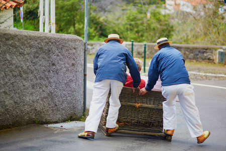 Famous toboggan riders moving traditional cane sledge downhill on the streets of Funchal, Madeira island, Portugalの写真素材