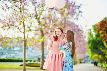 Two beautiful girls chatting outdoors in Paris on a spring dayの写真素材