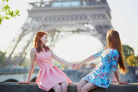 Two friends or sisters sitting near the Eiffel tower in Paris, Franceの写真素材