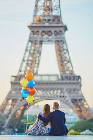Loving couple with bunch of colorful balloons looking at the Eiffel tower in Paris, Franceの写真素材