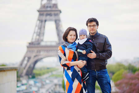 Happy family of three in Paris near the Eiffel tower. Mother, father and little son enjoying their vacation in Franceの写真素材