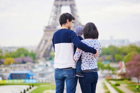 Happy family of three in Paris near the Eiffel tower. Mother, father and little son enjoying their vacation in Franceの写真素材