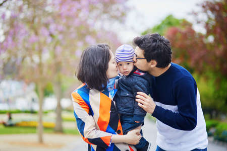 Happy family of three in Paris on a spring day with purple jacarandas in full bloom. Mother, father and little son enjoying their family time and vacation to Franceの写真素材