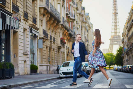 Romantic couple running across the street with Eiffel tower in background in Paris, Franceの写真素材